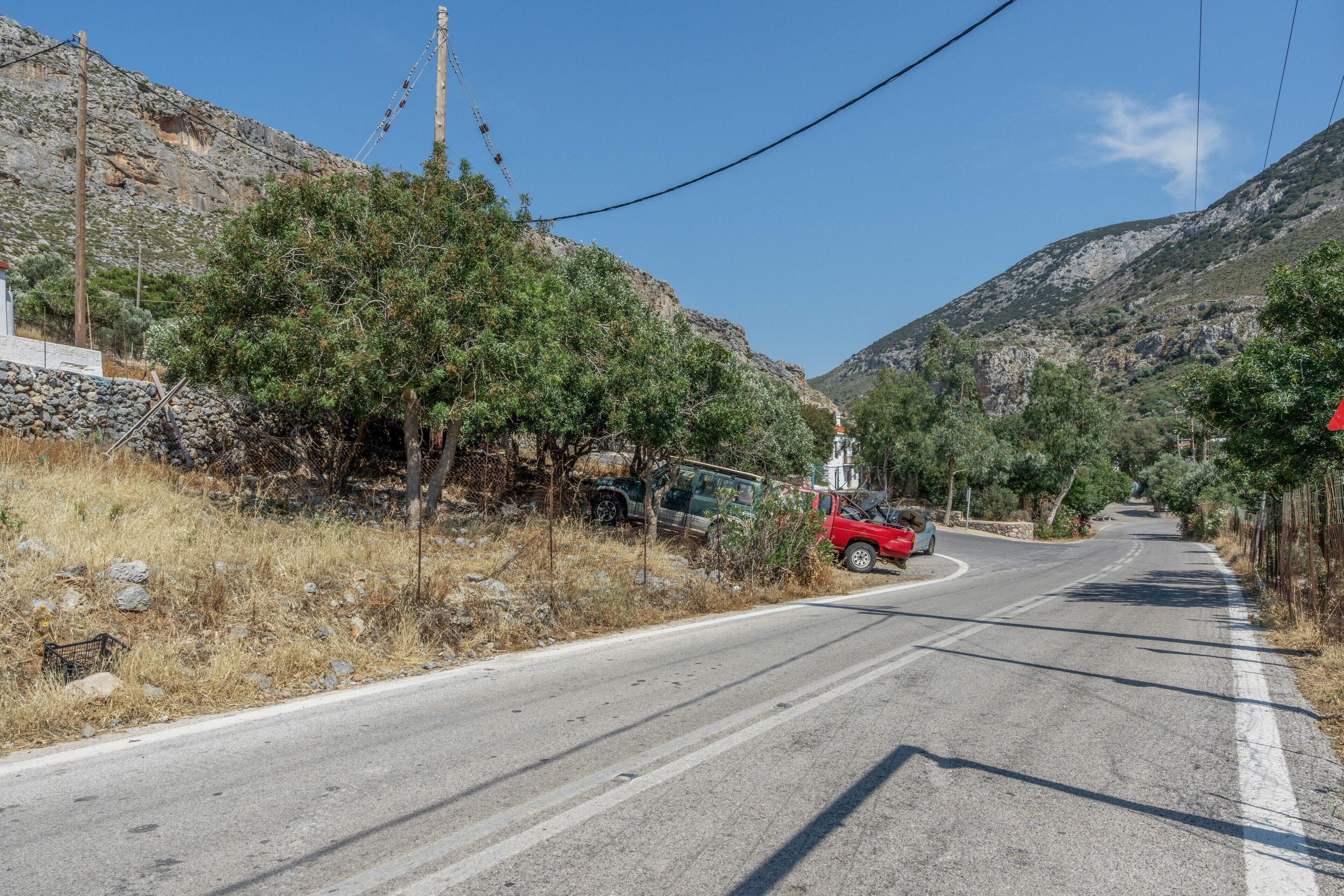 A road curving through a mountainous area with sparse vegetation and a few vehicles.