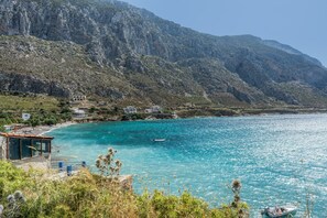 A coastal view with a mountain backdrop, clear turquoise sea, and a small boat. - Katerina's Studio '2' with Sea View and Private Balcony (Arginonta)