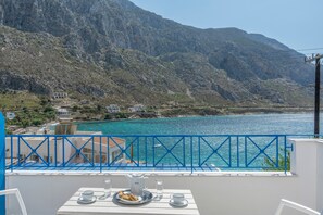 A balcony with a table set for two, overlooking a coastal area with mountains and a body of water. - Katerina's Studio '2' with Sea View and Private Balcony (Arginonta)