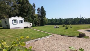 A mobile home with a small deck, surrounded by a grassy field and trees. - Mobile Home “Home” with Private Terrace (Plounévézel)