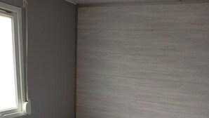 A single bed with a white duvet and two pillows, a window with blinds, and a wall with a textured finish. - Mobile Home “Home” with Private Terrace (Plounévézel)