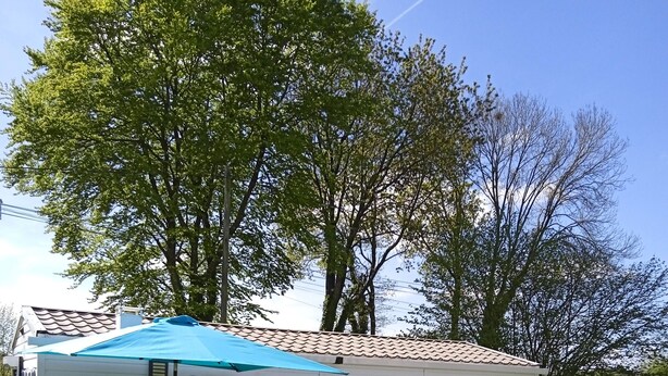A mobile home with a deck, white exterior, and a blue awning. - Mobile Home “Home” with Private Terrace (Plounévézel)