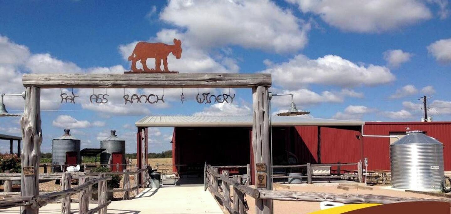 Une entrée sur le thème d’un ranch, avec une arche en bois, la silhouette d’une vache et un bâtiment rouge en arrière-plan.