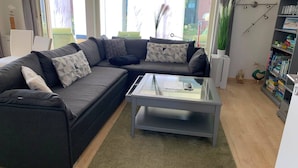 Una sala de estar moderna con un sofá modular, una mesa de centro de vidrio y una estantería.