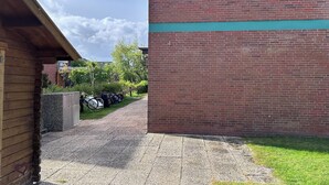 Un edificio de ladrillo con un cartel que dice 'Hus Utters' y un corredor cubierto que conduce a un área de estacionamiento con bicicletas.