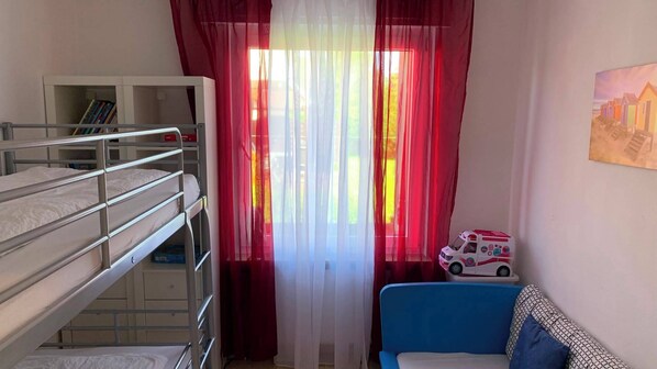 A bunk bed room with a bookshelf, a toy ambulance, and a painting on the wall.