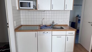 A compact kitchen with white cabinets, a Bosch dishwasher, a microwave, and a sink.
