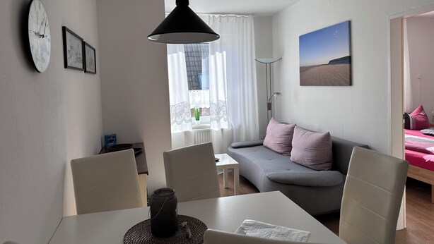 En moderne stue med spisebord, sofa og et billede på væggen.