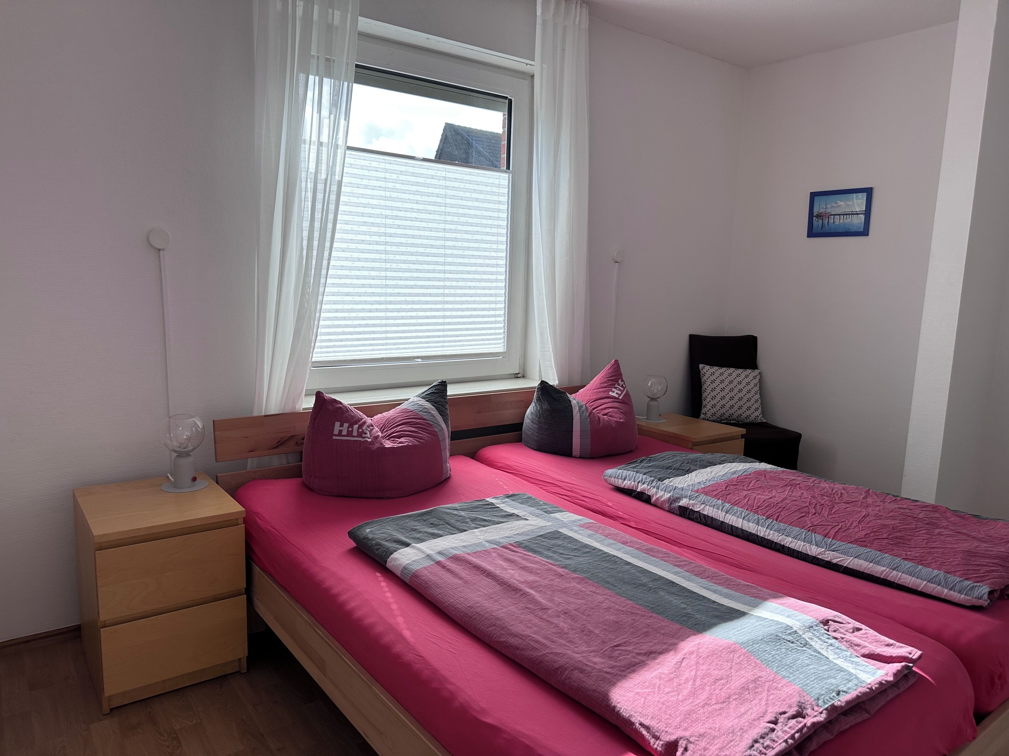 A bedroom with a bed, bedside tables, a window, and a picture on the wall.