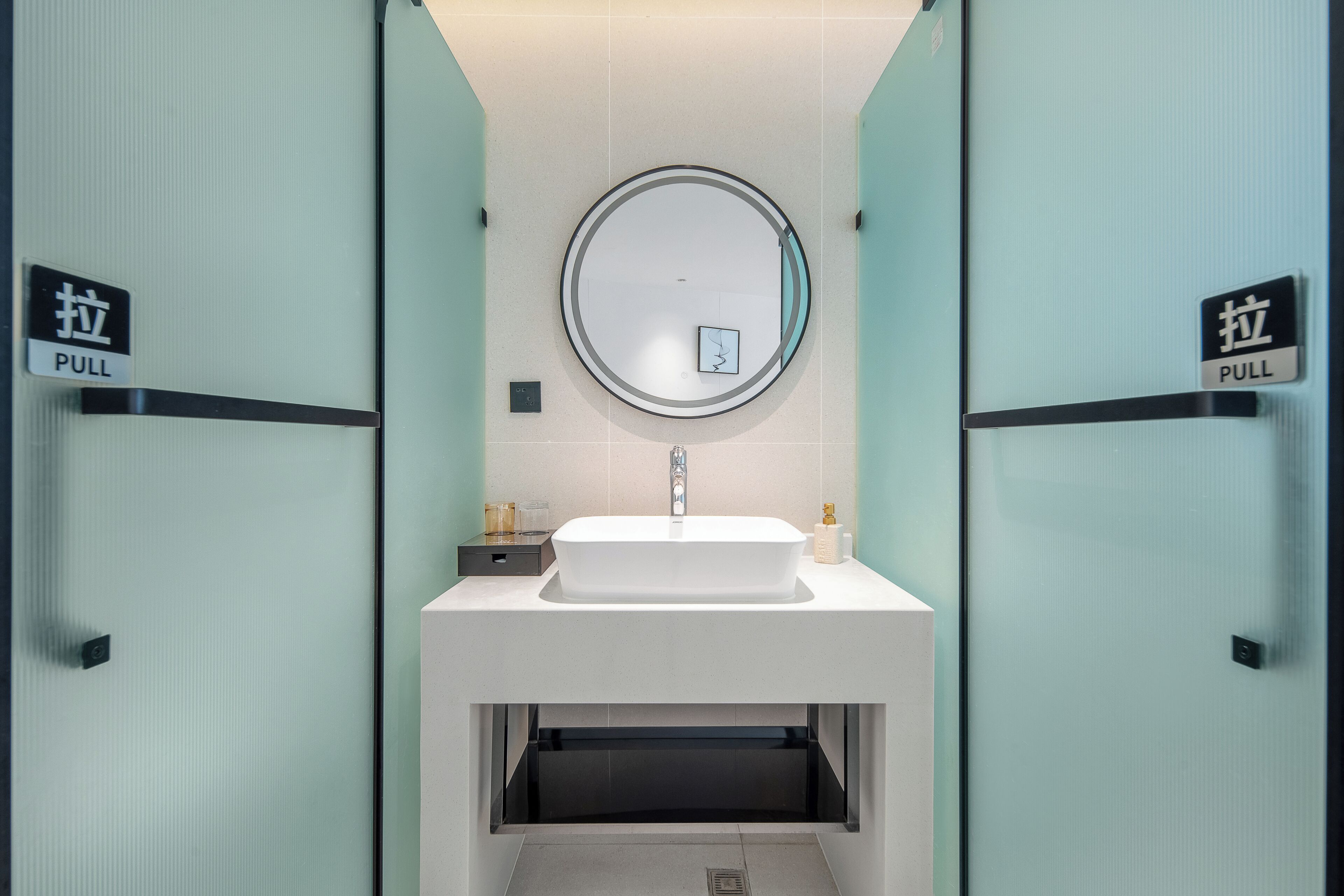 A bathroom with a sink, mirror, and two 'PULL' signs on doors.