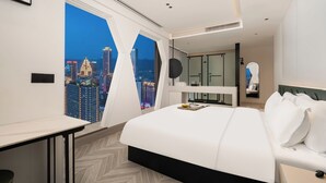 A modern hotel room with a large bed, a desk, and a view of a cityscape at night. - Key View Hotel (Chongqing)