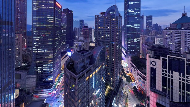 A cityscape with high-rise buildings, a curved glass structure, and a busy street with lights. - Key View Hotel (Chongqing)
