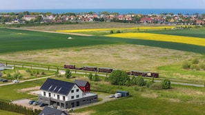 Ländliche Landschaft mit einem Zug, Feldern und einem Haus mit Solaranlage.
