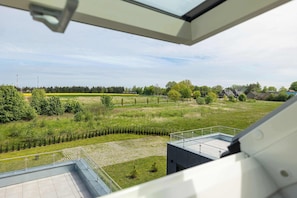 Blick aus einem Fenster auf eine grüne Landschaft mit Bäumen und einem Feld.