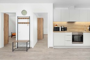 Eine moderne Küche mit weißen Schränken, einer Holz Arbeitsplatte, einem eingebauten Backofen und einer Mikrowelle.