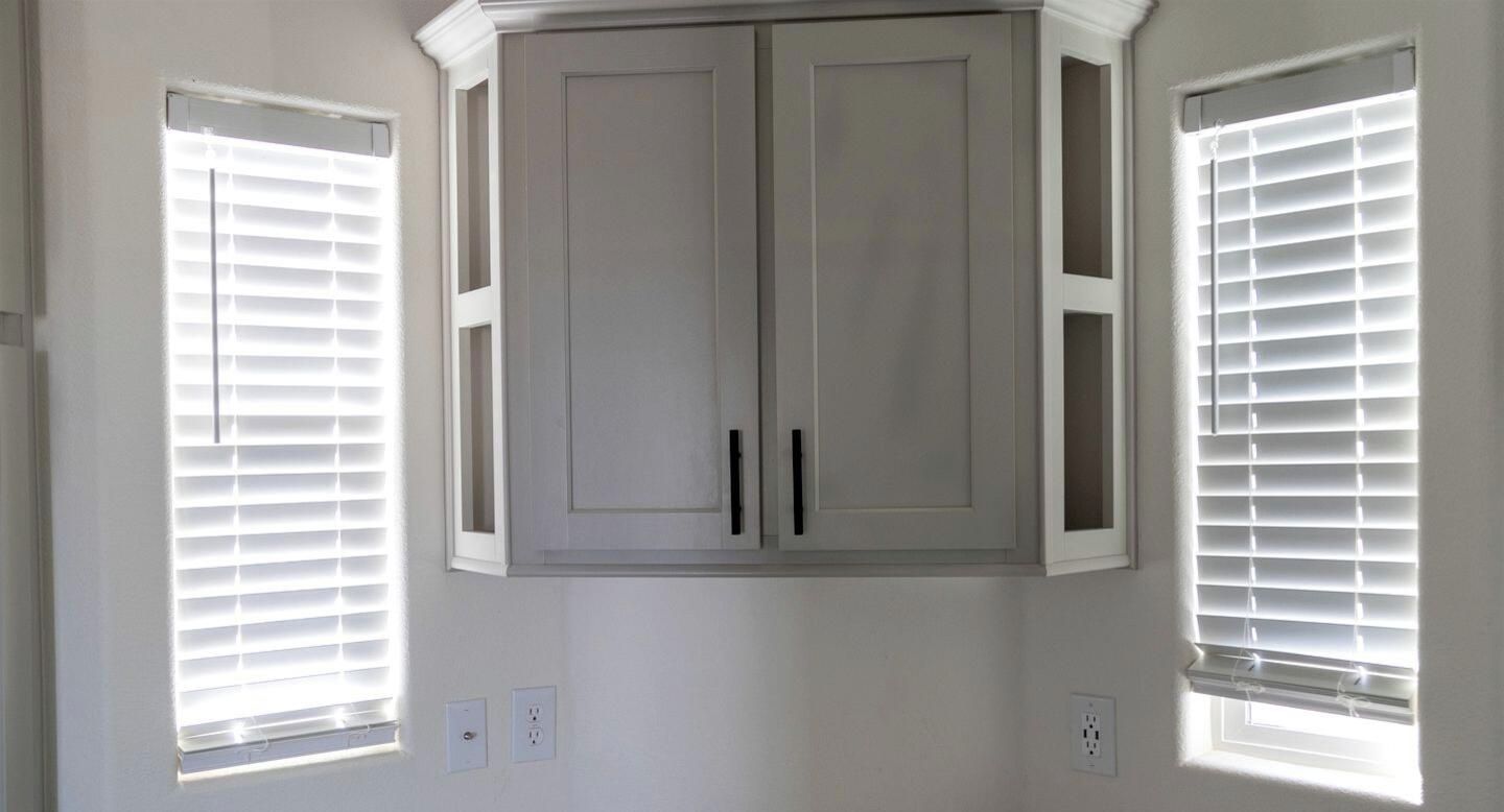 Una habitación con un armario empotrado y dos ventanas con persianas.