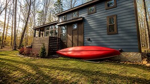 A house with a large red canoe in the yard, surrounded by trees. - Cozy Cabin Retreat with Loft Hideaway, Fire Pit & Nature Trails in Monteagle, Tennessee (Monteagle)