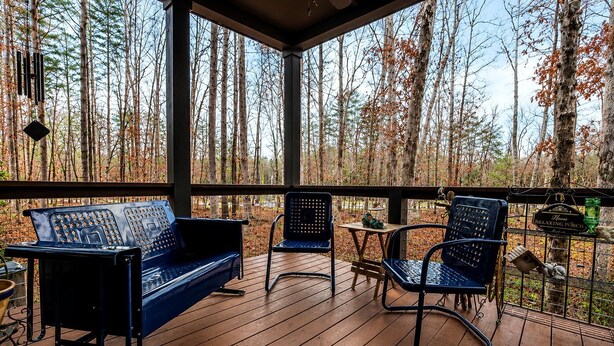 A covered outdoor deck with a wooden floor, a blue sofa, two chairs, and a small table. - Cozy Cabin Retreat with Loft Hideaway, Fire Pit & Nature Trails in Monteagle, Tennessee (Monteagle)