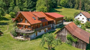 Ein großes Holzhaus mit rotem Dach, einem Balkon und einem Garten.