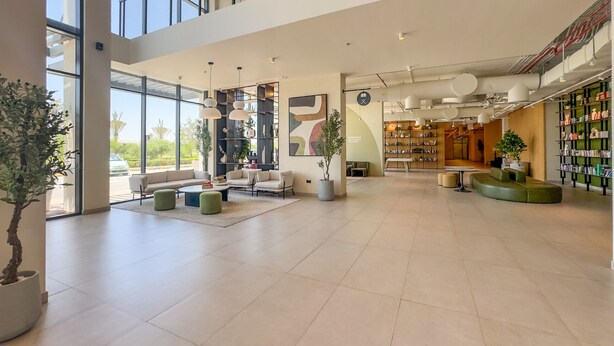Eine geräumige Lobby mit Sitzbereichen, einem großen Bücherregal und Blick ins Freie.