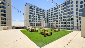Eine Dachterrasse mit Sitzgelegenheiten im Freien, einem Grill und Lichterketten.