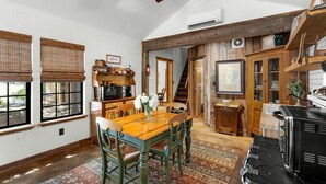 Ein Essbereich mit Holztisch und Stühlen, eine Kaffeebar und eine Küche mit Holzschränken und Geräten.