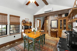 A dining area with a wooden table and chairs, a coffee bar, and a kitchen with wooden cabinets and appliances. - Chic, Renovated Barn with Hot Tub near the Heart of Fredericksburg Texas, Perfect for a Rustic Escape (Fredericksburg)