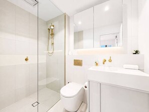 A modern bathroom with a glass-enclosed shower, a white toilet, and a vanity with a mirror. - Stylish Apartment Near Macquarie Uni & Metro (Macquarie Park)