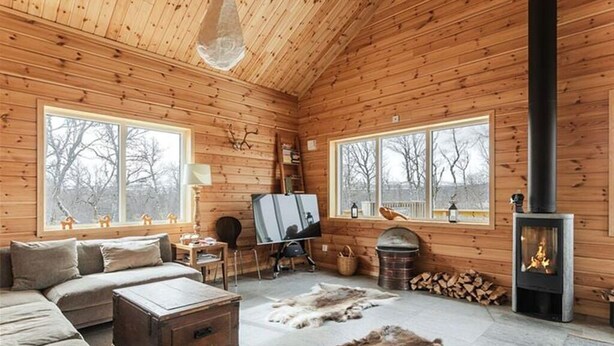 A log cabin interior with a sofa, fireplace, windows, and a painting on the wall. - Tännstoppet - Tänndalen (Tänndalen)