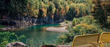 Un banc donnant sur une rivière paisible, avec une colline boisée en arrière-plan.