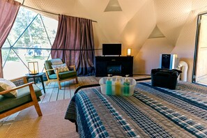 Una habitación tipo tienda de campaña con cama, zona de estar, televisión y chimenea.