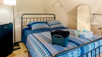 Ein Schlafzimmer mit Bett, Nachttisch, Lampe, Spiegel und Heizkörper.