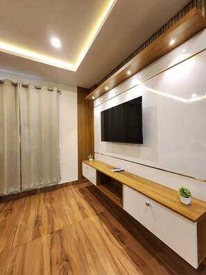 Uma sala de estar moderna com televisão de tela plana na parede, piso de madeira e um console de madeira embutido com gavetas.