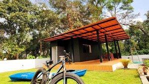 A covered outdoor area with a bicycle and a blue boat. - Neelambari Estate Stay (Madikeri)
