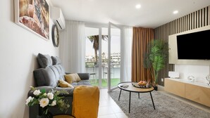 A living room with a sofa, a coffee table, a TV, and a sliding glass door leading to an outdoor area. - Vacation Apartment 'Infinity Summer' with Mountain View, Wi-Fi and Air Conditioning (Amarilla Golf)