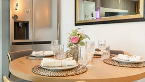 A dining table set with plates, glasses, and a vase with flowers. - Vacation Apartment 'Infinity Summer' with Mountain View, Wi-Fi and Air Conditioning (Amarilla Golf)
