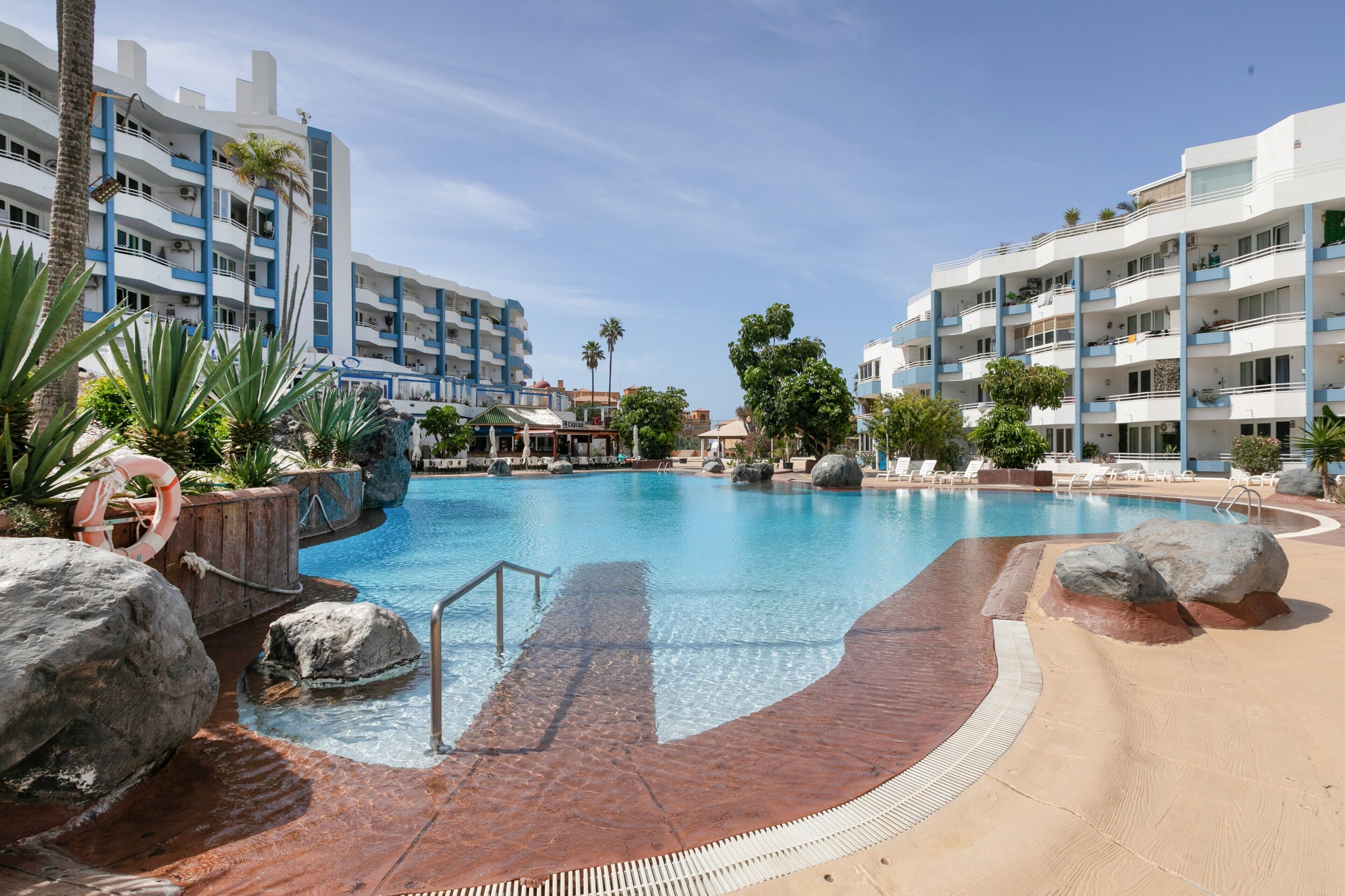 Un hôtel doté d’une piscine, de palmiers et offrant une vue sur un ciel dégagé.