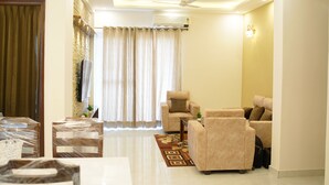 A living room with a sofa set, a dining table, and a patterned rug. - Harmony Haven: Luxurious 3BHK Haven for All. (Sahibzada Ajit Singh Nagar)