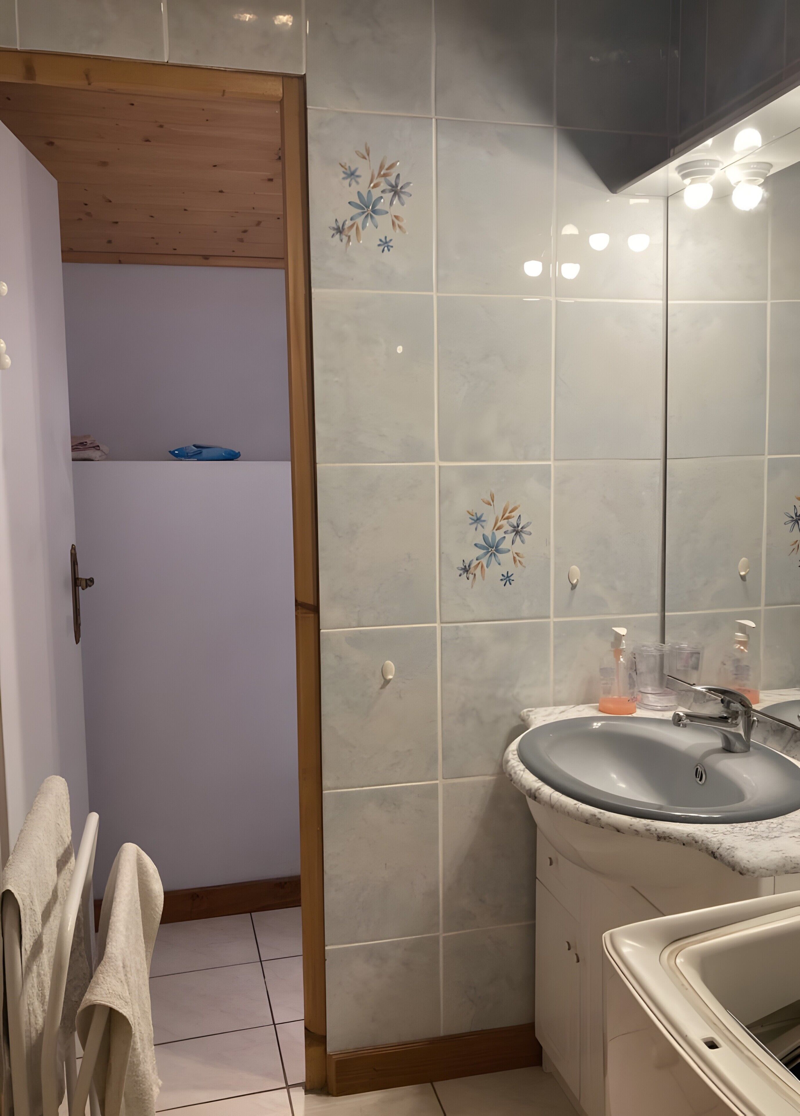 Ein Badezimmer mit Waschbecken, Spiegel und dekorativen Fliesen.