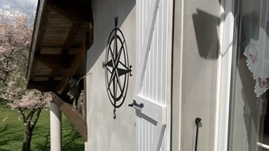 A building with a white exterior, a wooden overhang, a compass decoration, and a window with a butterfly sticker. - Holiday Home "Gîte Des 4 Lacs" with Mountain View, Private Terrace and Wi-Fi (Vertamboz)
