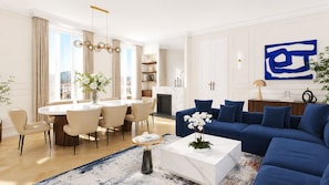Ein modernes Wohnzimmer mit einem blauen Sofa, einem runden Esstisch mit Stühlen, einem Couchtisch mit Blumenvase und einem großen abstrakten Gemälde an der Wand.