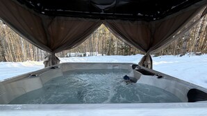 A hot tub with a view of a snowy forest.