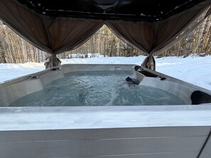 Ein Whirlpool mit Blick auf einen verschneiten Wald.