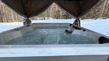 A hot tub with a view of a snowy forest.