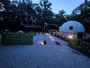 Un espace jardin agrémenté d’un belvédère, d’une construction de forme sphérique et d’un éclairage décoratif.