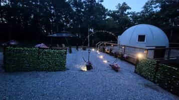 Un espace jardin agrémenté d’un belvédère, d’une construction de forme sphérique et d’un éclairage décoratif.
