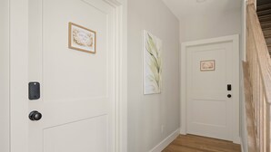 A hallway with white doors, a remote control, and framed artwork on the walls. - Wild Rose Suite (Rome)