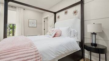 Ein Schlafzimmer mit einem Bett, einem Nachttisch mit Lampe und einem Fenster mit Vorhängen.