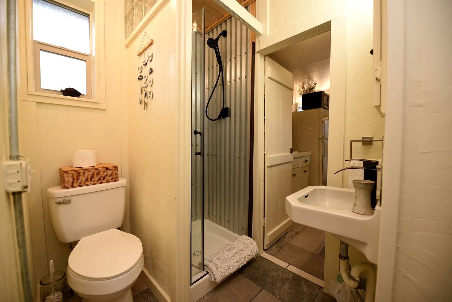 A compact bathroom with a toilet, a glass-enclosed shower, and a sink.