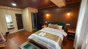 A bedroom with a large bed, wooden walls, a mirror, and a green rug.